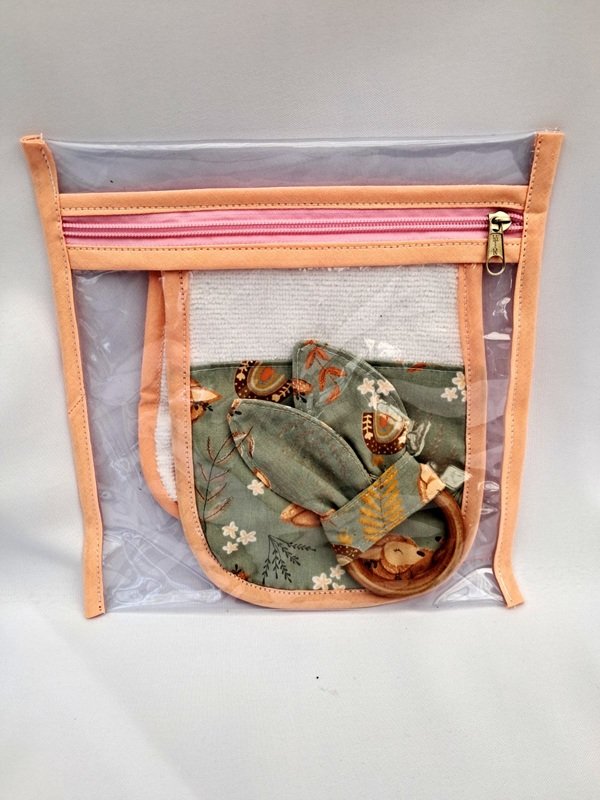 Neceser transparente color salmón con bolsita interior y accesorios de bebé