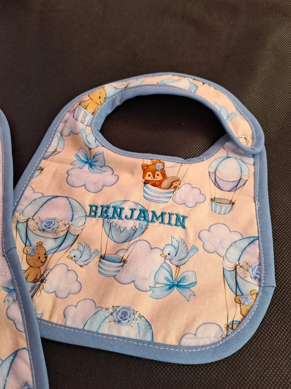 Babero estampado con globos aerostáticos y el nombre Benjamín bordado en celeste